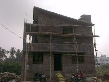 The house as bare blockwork with bamboo scaffolding, before plastering — in Pannimadai, Coimbatore